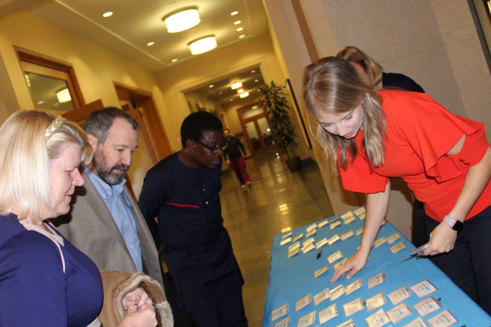 Image 1 of 15 People gathered around the welcome table, looking at nametags